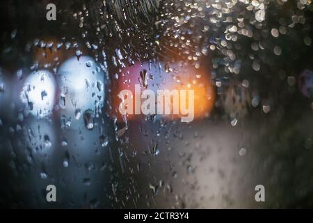 Regentage, Regen fällt auf das Fenster mit verschwommener Ampel, regnerischem Wetter, Regen und Bokeh Stockfoto