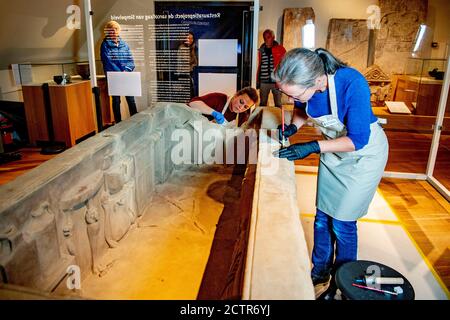 Ein Mitarbeiter, der während der Restaurierung am Sarkophag arbeitet.EIN zerbrochener römischer Sarkophag im Nationalmuseum der Altertümer in Leiden wird restauriert. Die 2.5 Meter lange Sandsteinkiste wurde 1930 bei Simpelveld in Limburg gefunden. Frühere Forschungen über das Knochenmaterial haben festgestellt, dass die eingeäscherte Frau zwischen 35 und 50 Jahre alt war, als sie starb und ein gutes Leben ohne harte Arbeit geführt hatte. Stockfoto