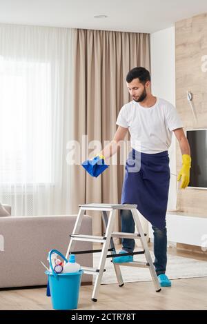 Mann klettert Leiter, um die Decke zu reinigen. Reinigungsdienstkonzept Stockfoto