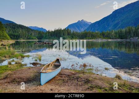 Blasses blaues Kanu mit Rudern bereit, wartet am Ufer neben Buttle Lake. Stockfoto