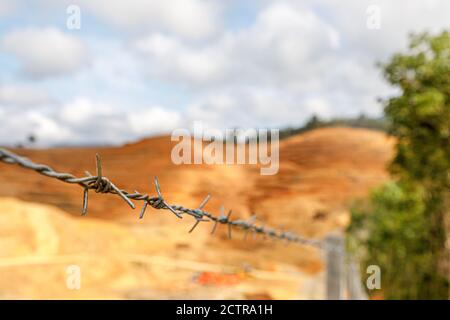 Sigapon, Sabah, Malaysia: Nahaufnahme mit flachem DoF eines Stacheldrahtes vor den frisch neu gestalteten Terrassen einer Ölpalmenplantage in Keningau Stockfoto