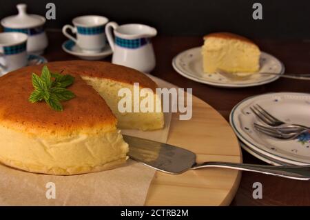 Tabelle, in der wir einen japanischen Käsekuchen neben sehen Einige Tassen für Tee oder Kaffee Stockfoto