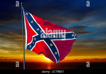 Spektakulärer Sonnenaufgang hinter einer konföderierten Flagge, die im Wind weht Gegen einen Sonnenhimmel Stockfoto