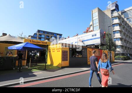 Ein Paar, das am trendigen Essig Yard in der St Thoams Street in Southwark, SE London, Großbritannien, vorbeiläuft Stockfoto