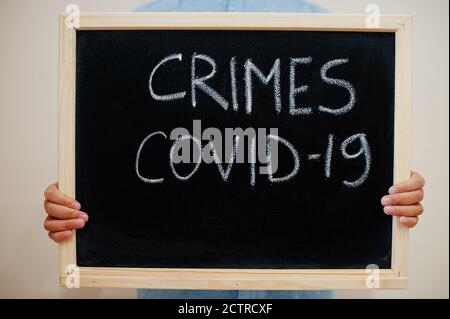 Crimes Covid-19. Coronavirus-Konzept. Junge halten Inschrift auf dem Brett. Stockfoto