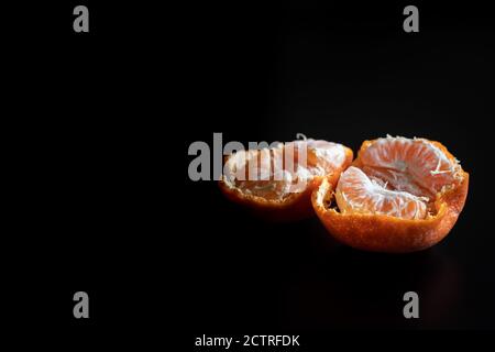 Frisch geschälte Mandarine / Clementine auf einem schwarzen Tisch Stockfoto