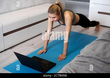 Fitness-Mädchen Ausübung beobachten Online-Videos auf Laptop in Das Wohnzimmer zu Hause Stockfoto