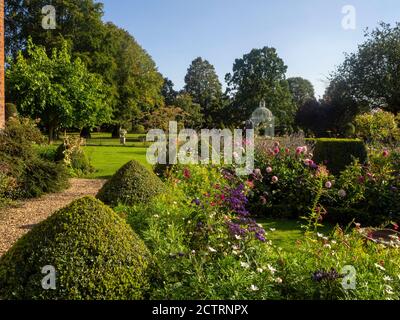 Chenies Manor Garden, wunderschön in der Spätsommersonne. Clipped Box topiary, rosa und blau krautigen Pflanzen und Dahlien mit der Parterre und Pagode. Stockfoto