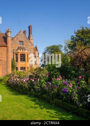 Chenies Herrenhaus und Garten an einem sonnigen Septembernachmittag.Bunte Dahlien, krautige Pflanzengrenzen, Rasen.Dahlia 'Sandra', Dahlia Karma Prospero Stockfoto