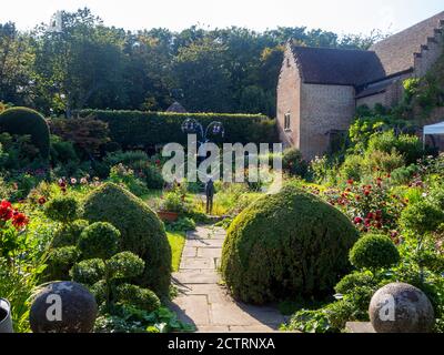 Chenies Manor House versunkenen Garten an einem sonnigen Mitte September Nachmittag, 2020. Bunte Dahlien Sorten in terrassierten Pflanzengrenzen, topiary, Skulpturen. Stockfoto
