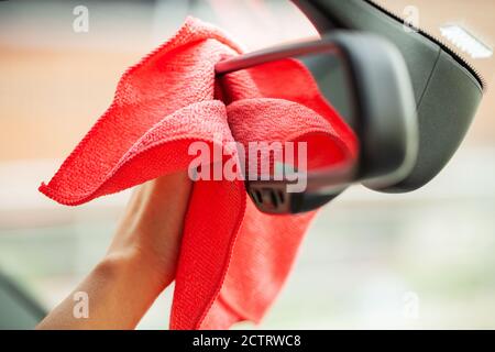 Nahaufnahme einer Frau, die den Innenraum des Autos mit rotem Lappen abwischt. Stockfoto