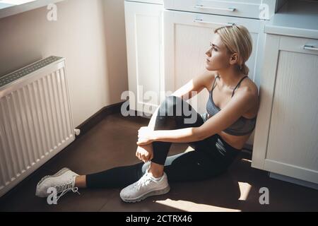 Junge kaukasische Fitness-Frau in Sportbekleidung ist mit einer Pause Von der Ausübung entspannen auf dem Boden Stockfoto