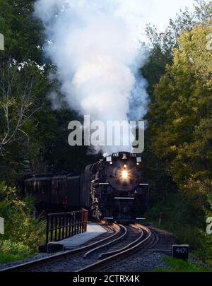 Steam Engine 765 rundet die Kurve und überquert während des Herbstlaufs eine Brücke über den Cuyahoga River im Cuyahoga Valley National Park. Stockfoto