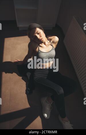 Obere Ansicht Foto von einer blonden Frau in Sportswear entspannend Auf dem Boden nach Fitness-Übungen zu Hause Stockfoto