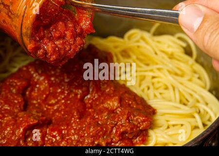Fügen Sie Bolognese Sauce auf Spaghetti in Topf. Kochen Pasta Bolognese zu Hause Stockfoto