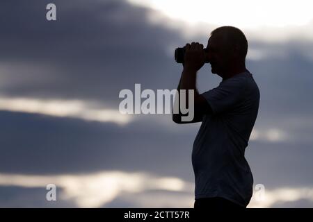 Ein Mann in Silhouette mit einem Fernglas Stockfoto