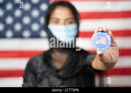 Selektiver Fokus auf Hände, Mädchen mit Hijab oder Kopfbedeckung und Maske getragen zeigen Ich habe Sticker mit US-Flagge als Hintergrund gewählt - Konzept der Abstimmung während Stockfoto