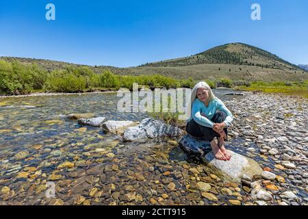 USA, Idaho, Sun Valley, Frau auf Felsen im Fluss sitzend Stockfoto