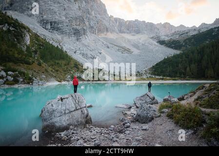 Italien, Südtirol, Cortina d Ampezzo, Sorapis-See, Männer, die auf Felsformationen stehen und die Aussicht genießen Stockfoto