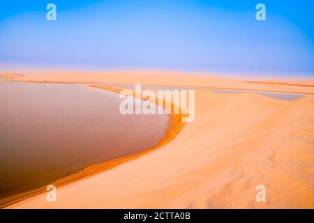 Wüste bei Sonnenaufgang, goldene Farbe und fast abstrakte Farben geschichtet, bevor die Sonne über Sealine Desert Dünen und Binnensee mit seinem langen geschwungenen b aufgeht Stockfoto