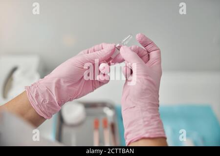 Weibliche Kosmetikerin Hände halten Ampulle mit Lösung Stockfoto