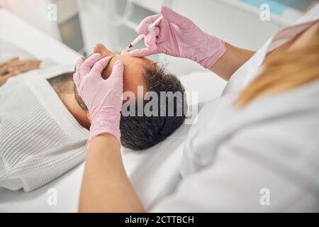 Junger Mann erhält kosmetische Injektionen im Wellnesscenter Stockfoto