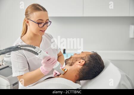 Schöner junger Mann mit Laser-Haarentfernung Verfahren Stockfoto