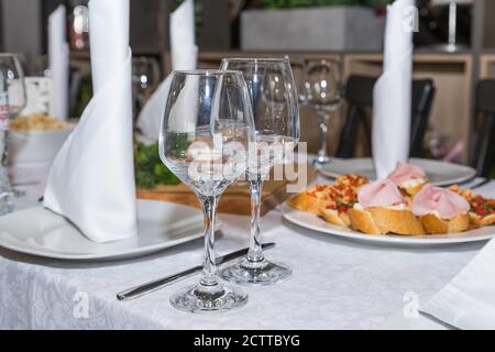 Leere Gläser im Restaurant.serviert für einen Banketttisch. Weingläser mit Servietten, Gläser und salads.catering Dienstleistungen Hintergrund mit Snacks und Stockfoto