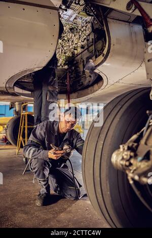 Flugzeugarbeiter, der das Flugzeug unter dem Flugzeug kontrolliert Stockfoto