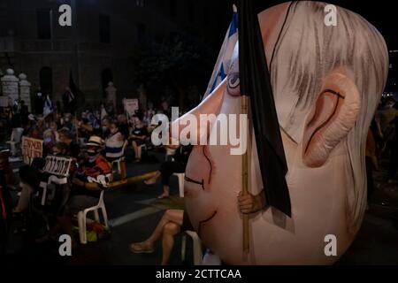 JERUSALEM, ISRAEL - 24. SEPTEMBER 2020: Ein Protestler trägt ein Aufblasbares des israelischen Ministerpräsidenten Benjamin Netanjahu, während Demonstranten auf Stühlen sitzen, um den sozial-distanzierenden Vorschriften zu folgen, während einer Demonstration vor Benjamin Netanjahus offiziellem Wohnsitz inmitten einer landesweiten Sperre, die darauf abzielt, die Coronavirus-Pandemie am 24. September 2020 in Jerusalem, Israel, einzudämmen. Eine Welle von Protesten hat Israel in den letzten Monaten überschwemmt, um Netanjahus Rücktritt wegen seiner Anklage wegen Korruptionsvorwürfen und des Umgangs mit der Coronavirus-Pandemie zu fordern. Stockfoto