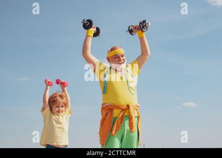 Sport- und Trainingskonzepte. Wir trainieren jeden Tag. Sport für Kinder. Glücklicher kleiner Junge mit Großvater macht Übungen mit Hanteln. Kind Stockfoto