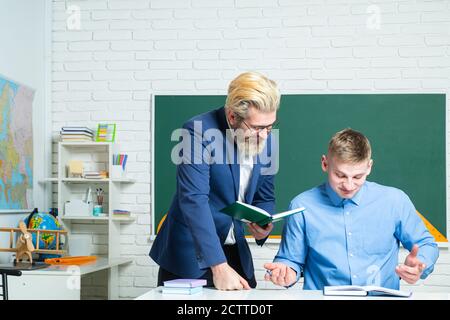 Schüler und Lehrer an der Hochschule. Kursleiter in der Schulungsklasse mit Kursteilnehmern. Portrait eines jungen Lehrers, der einem Schüler während des Unterrichts hilft. Stockfoto