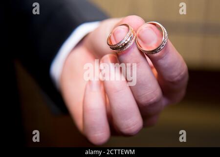 Goldene Eheringe in der Hand des Mannes. Nahaufnahme. Stockfoto