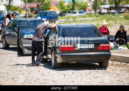 Gori, Georgia - Juni 13 2017: Ein Mann mit grauen Haaren steht auf dem Stadtmarkt neben dem Auto und spricht mit dem Fahrer Stockfoto