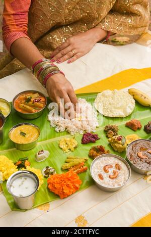 Onam sadhya, indische Frauen essen mit Hand gekochten Reis, serviert für Kerala Indian Festival mit Curries Sambar, Avial, Thoran, Papadum, Payasam, Banana Stockfoto