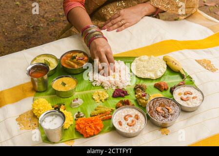 Onam sadhya, indische Frauen essen mit Hand gekochten Reis, serviert für Kerala Indian Festival mit Curries Sambar, Avial, Thoran, Papadum, Payasam, Banana Stockfoto