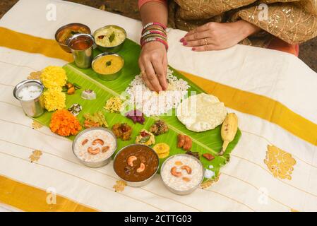 Onam sadhya, indische Frauen essen mit Hand gekochten Reis, serviert für Kerala Indian Festival mit Curries Sambar, Avial, Thoran, Papadum, Payasam, Banana Stockfoto