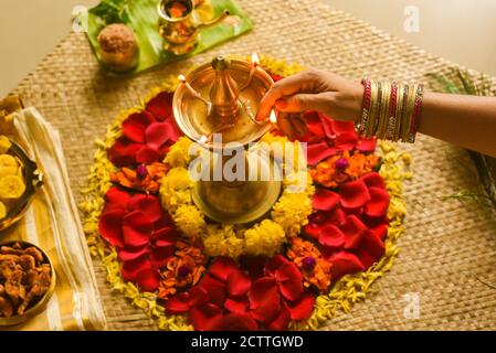 Frauen Beleuchtung Lampe und traditionelle Blumenbeet für Onam, Erntefest von Kerala Indien. Frische Blumenteppich Blumenmuster für indische Festival gemacht Stockfoto