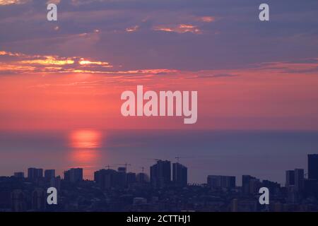 Reflexionen des Sonnenlichts über dem Meer mit Gruppe von Wolkenkratzer und Baustelle im Vordergrund Stockfoto