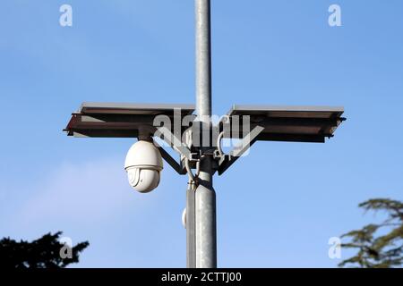 Weiß Ball geformt drehbar wasserdicht Überwachungskamera CCTV powered by Zwei kleine Sonnenkollektoren auf der Oberseite auf starkem Metall montiert Versorgungsmast Stockfoto