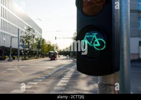 Ampel für Fahrräder an einem sonnigen Sommertag mit verschwommenem Blick auf die Stadt im Hintergrund. Grünes Licht für Sportkonzept. Gesundes Leben Stockfoto