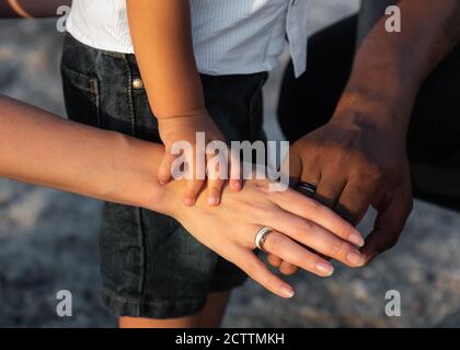 Nahaufnahme von drei multirassischen Familienmenschen stapeln ihre Handflächen. Multirassische Liebe und Integration zwischen Vielfalt. Konzept der rassischen Toleranz Stockfoto