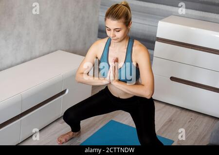 Junge Frau, die im Wohnzimmer hockt und trainiert Zu Hause Stockfoto