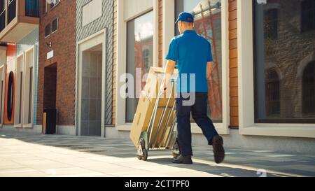 Delivery man schiebt Hand Truck Trolley voll von Karton-Boxen, Pakete für die Lieferung. Professioneller Kurier Arbeitet Effizient, Schnell. Spaziergänge Stockfoto
