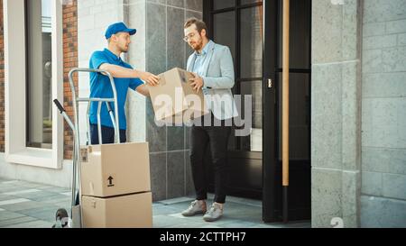 Delivery man schiebt Hand Truck Trolley voller Karton-Boxen Hände-Paket an einen Kunden, der dann unterzeichnet elektronische POD-Gerät. Kurier Liefert Stockfoto