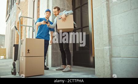 Delivery man schiebt Hand Truck Trolley voller Karton-Boxen Hände-Paket an einen Kunden, der dann unterzeichnet elektronische POD-Gerät. Kurier Liefert Stockfoto