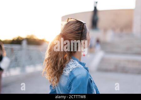 Junge Frau, die nach oben berühmten Ort Denkmal Rückansicht in Sonnenuntergang Stockfoto