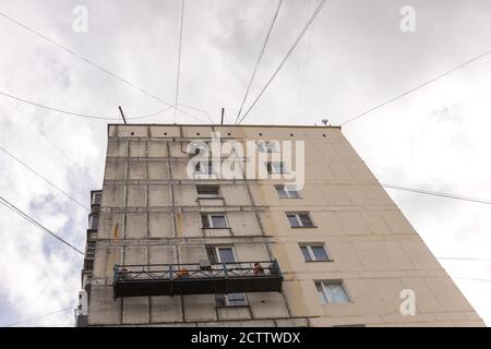 Renovierung der Fassade eines alten Gebäudes. Arbeiter in einer hängenden Baustation Stockfoto