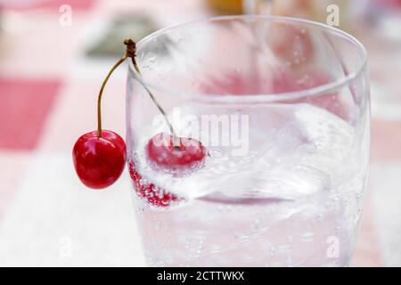 Kirschen im Glas mit Mineralwasser aus der Nähe. Selektiver Fokus Stockfoto