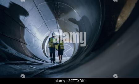 Zwei Ingenieure Der Schwerindustrie, Die In Rohr Gehen, Laptop Verwenden, Diskussion Haben, Schweißprüfung. Bau von Öl, Erdgas und Brennstoffen Stockfoto